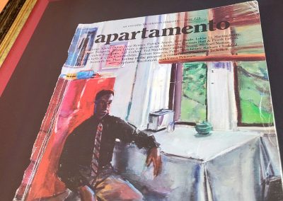 A close up on the red spacers that keep the floated artwork (a well-thumbed magazine cover) away from the glass.